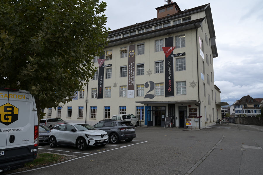 Mehrstöckiges Gebäude mit Firmenbannern und Parkplatz, Standort des Showrooms in Niederlenz